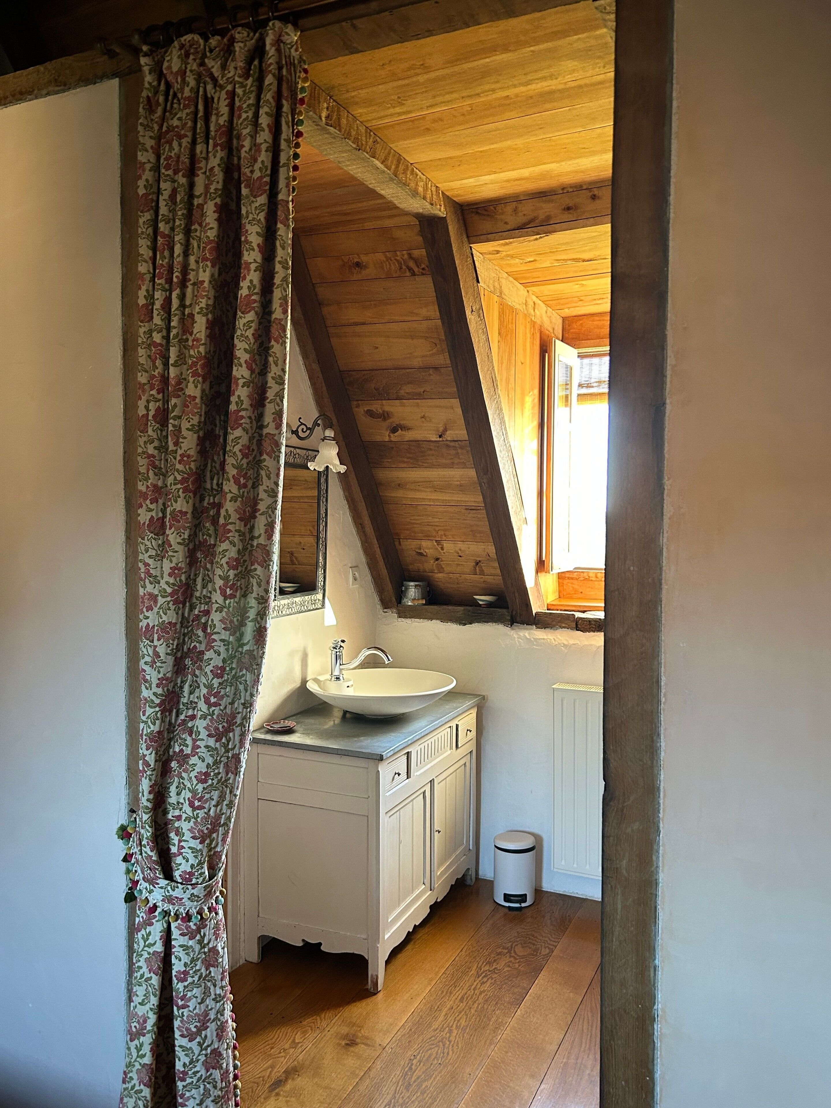 Un baño con techo de madera, un lavamanos blanco y un espejo.