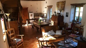 A spacious living area with a wooden dining table, a sofa, and a kitchen in the background. - Guest Room 'La Grange De La Bonaurie - Havane' with Shared Terrace and Garden (Anglars-Saint-Félix)
