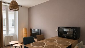 Een moderne eetruimte met een houten tafel, vier stoelen, een televisie en een magnetron.