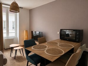 Un espace repas moderne comprenant une table en bois, quatre chaises, un téléviseur et un four à micro-ondes.