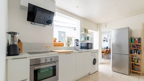 Eine moderne Küche mit Einbauofen, Mikrowelle und Waschmaschine, einem großen Fenster und Blick auf den Essbereich.