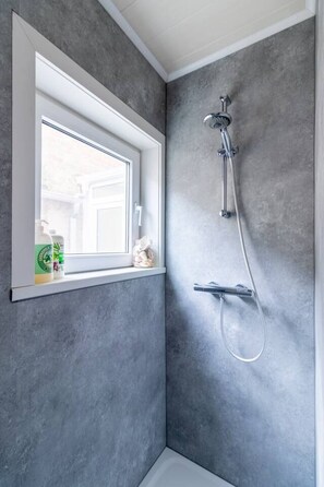 A bathroom with a shower, a window, and a towel rack.