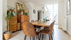 Ein Essbereich mit einem Holztisch, braunen Stühlen, einem Schrank und einem Topfpflanzen.