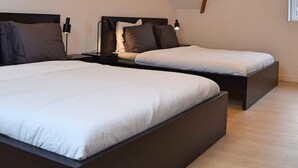 Une chambre avec deux lits, des poutres en bois et un plafond en pente.