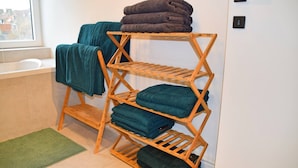 Un étendoir en bois avec des serviettes pliées dans une salle de bain.