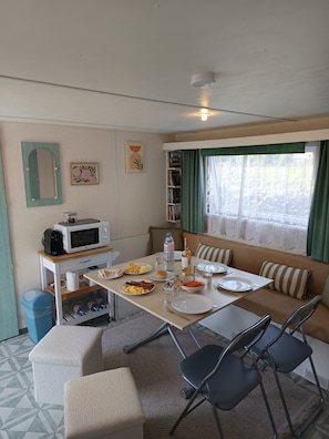 A compact kitchen with a microwave, coffee maker, and a small dining table set for two. - Escape Baie de Somme: Mobil home _ Vironchaux (Vironchaux)