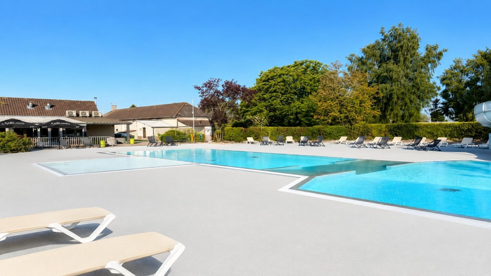 A swimming pool with lounge chairs and a building in the background.