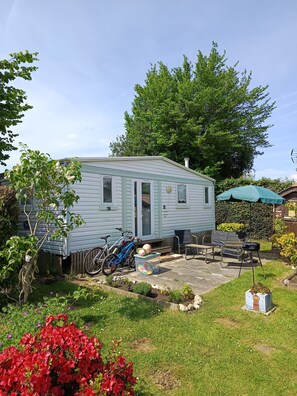 A mobile home with a patio area, a bicycle, and a green umbrella. - Escape Baie de Somme: Mobil home _ Vironchaux (Vironchaux)