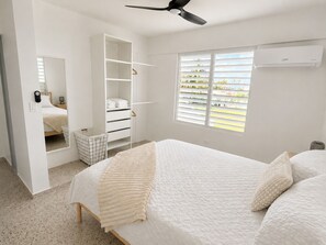 Un dormitorio con cama, armario, espejo y ventana con persianas.