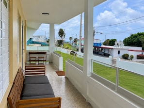 Un balcón con banco, mesa y vista a la calle.