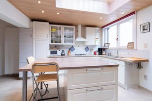 Eine moderne Küche mit weißen Schränken, einem Holztisch und einem Fenster mit rotem Vorhang.