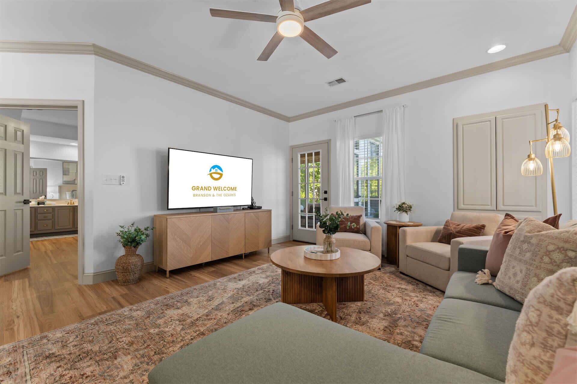 A modern living room with a television, sofa, coffee table, and a ceiling fan.