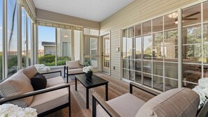 A covered patio with a sofa, a table, and a chair. - Birdies View Golf View Patio (Branson)