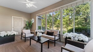 A sunroom with a ceiling fan, large windows, a sofa, a coffee table, and potted plants. - Birdies View Golf View Patio (Branson)