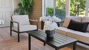 A sunlit room with a sofa, two chairs, a coffee table, and a potted plant. - Birdies View Golf View Patio (Branson)