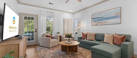 A spacious living room with a sofa, armchairs, a coffee table, and a television.