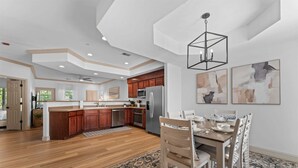 A spacious kitchen with wooden cabinets, a central island, and a dining area with a table set for four. - Birdies View Golf View Patio (Branson)