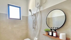 A bathroom with a toilet, sink, shower, and a small window.