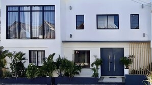 A modern two-story house with large windows, a flat roof, and a front door.