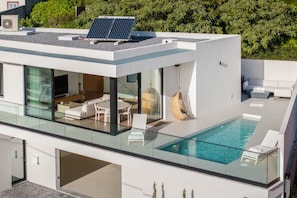 Een modern gebouw met een dakterraszwembad, glazen wanden en zonnepanelen.