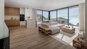 A modern living room with a sofa, coffee table, and a view of the sea. - Superb modern villa with pool in Calheta|Amani (Arco Da Calheta)