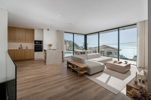 Een moderne woonkamer met een bank, salontafel en uitzicht op zee.