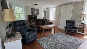 A living room with a sofa, armchair, coffee table, rug, and a lamp on a side table. - Secluded 1860 Stone House recently remodeled on the Upper Iowa River by Bluffton (Decorah)