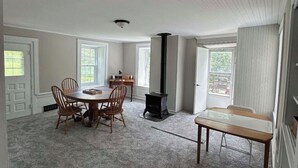 A spacious room with a large round table, several chairs, a fireplace, and a view of the outdoors. - Secluded 1860 Stone House recently remodeled on the Upper Iowa River by Bluffton (Decorah)