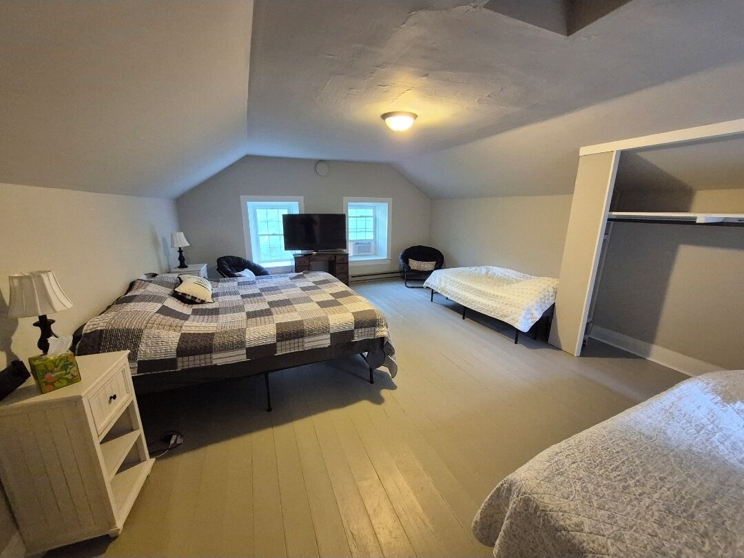 Et soveværelse med to senge, et fjernsyn, et skrivebord og et vindue.