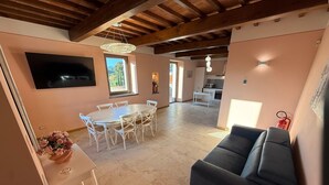 A spacious living area with a dining table, sofas, and a kitchen in the background. - Spacious Holiday Home With Shared Pool in Poppi (Poppi)