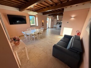 Un'ampia zona giorno con tavolo da pranzo, divani e una cucina sullo sfondo.