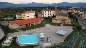 A residential area with a swimming pool, stone buildings, and a view of distant mountains. - Spacious Holiday Home With Shared Pool in Poppi (Poppi)