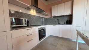 A modern kitchen with white cabinets, a built-in microwave, and a stainless steel range hood. - Spacious Holiday Home With Shared Pool in Poppi (Poppi)