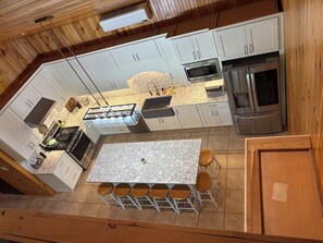 Een moderne keuken met witte kasten, een centraal eiland met krukken, een inbouwoven en een koelkast.