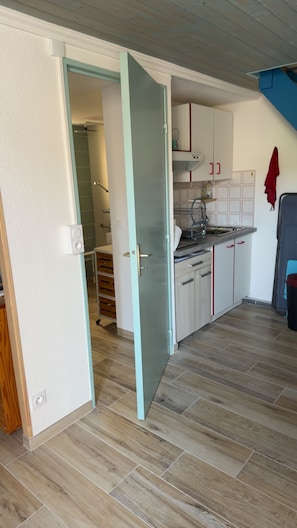A kitchen with white cabinets, a wooden floor, and a red towel hanging on the wall.
