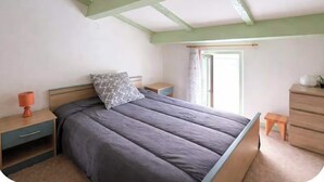 Een slaapkamer met een bed, nachtkastje, kaptafel en een raam.