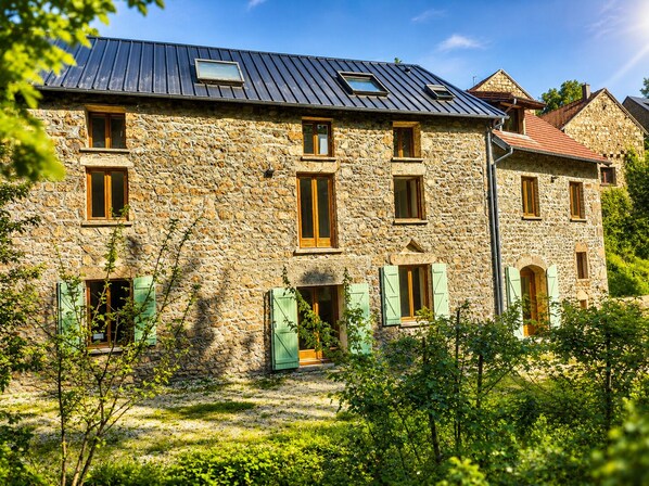 Un bâtiment en pierre doté de nombreuses fenêtres et d’un toit en pente.