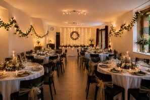Une salle de banquet avec des tables rondes, des chaises et des décorations festives.