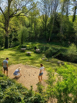 Un jardin avec un sentier de terre, des arbres et un petit étang.