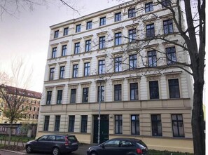Ein mehrstöckiges Gebäude mit einer symmetrischen Fassade, großen Fenstern und einem zentralen Eingang.