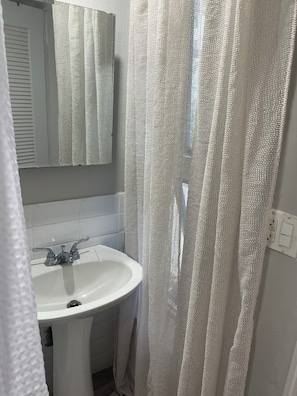 A bathroom with a white sink, a mirror, and a shower curtain.