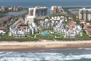 Ein Hotel an der Küste mit mehreren Gebäuden, einem zentral gelegenen Pool und Blick auf den Strand.