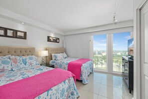 Ein Hotelzimmer mit zwei Betten, einem Fernseher und einem Balkon mit Blick auf die Stadt.