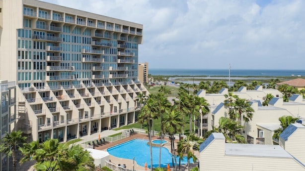 Un hotel amb diverses plantes, una piscina i vistes a l'oceà.