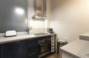 A modern kitchen with a stainless steel range hood, a toaster, a coffee maker, and a trash can. - Spacious, recently renovated apartment near the Louvre (Île-de-France)