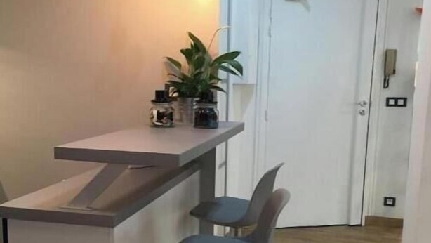 Een keukenhoek met een bar, twee barkrukken, hanglampen en een potplant.