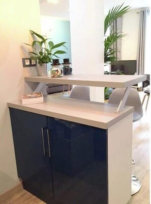 A modern kitchen with a dark blue cabinet, a white countertop, and a built-in sink. - Spacious, recently renovated apartment near the Louvre (Île-de-France)