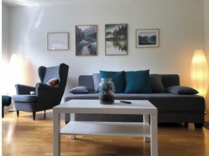 Ein modernes Wohnzimmer mit Sofa, Sessel und Couchtisch.
