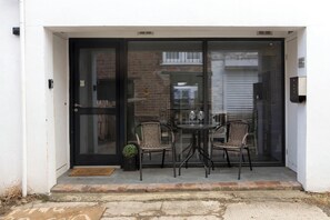 A glass door entrance with a small table and two wicker chairs outside a building. - Spacious Pet Friendly Home in Central Cheltenham. Sleeps 6 FREE Parking! (Cheltenham)