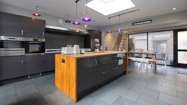Une cuisine moderne dotée d’un îlot central, d’appareils électroménagers en acier inoxydable, de luminaires suspendus et d’une lucarne.